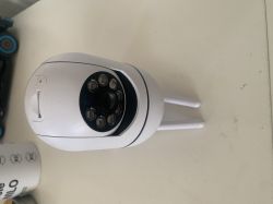 A white surveillance camera with two antennas stands on a light-colored surface.