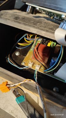 Wnętrze urządzenia elektronicznego z widoczną płytką drukowaną i przewodami.