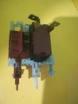 Zbliżenie na mechanizm blokady drzwi z przełącznikiem na żółtym tle.