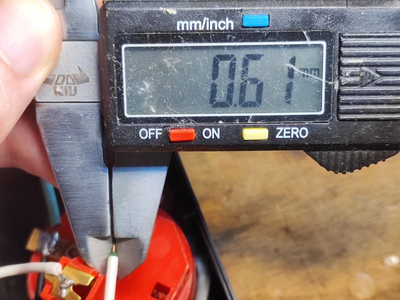 Pomiar średnicy przewodu za pomocą suwmiarki, wskazujący 0,61 mm.