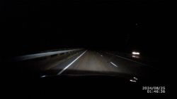 Widok z samochodu na nieoświetloną autostradę w nocy z włączonymi światłami drogowymi.