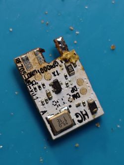 RE705-MB-v0.1 circuit board module with exposed electronic components and resin residue.