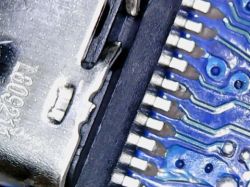 Zbliżenie na uszkodzone złącze USB-C i ścieżki na niebieskiej płytce PCB