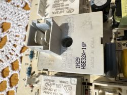 Szara kostka elektryczna HONGFA H3FA na płytce PCB, z widocznymi metalowymi stykami