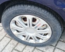 Zbliżenie na koło samochodu z oponą 175/60 R14 i srebrną felgą z logo EVO Race.