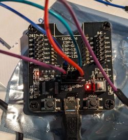 Close-up of an ESP8266 module with connected wires and two flashing red LEDs.