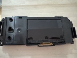 Wyświetlacz LCD zamontowany w czarnej plastikowej obudowie na jasnym tle.