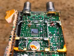 Zbliżenie na płytkę PCB z układem scalonym i komponentami wewnątrz tunera satelitarnego.