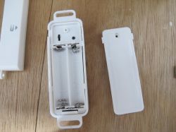 Open Battery Case Open plastic battery case with a white cover next to it.