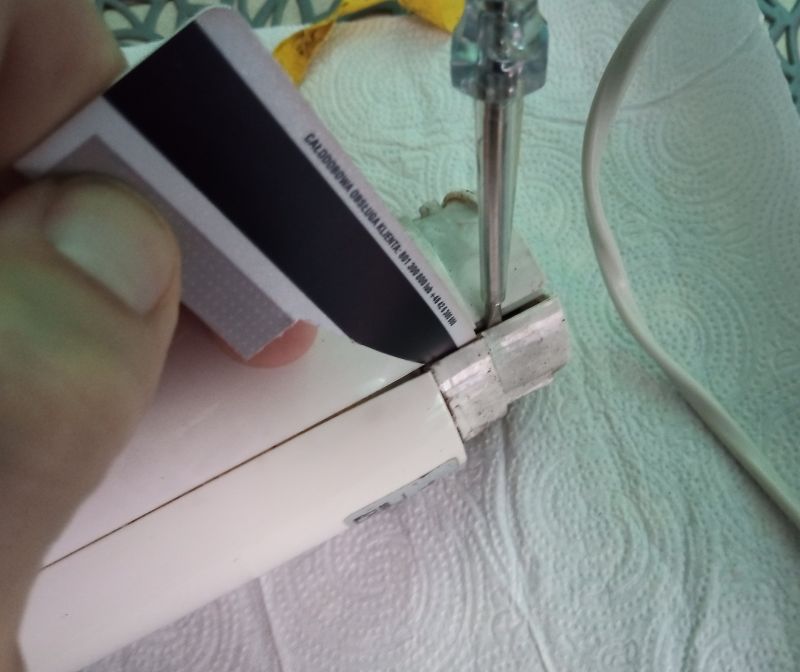 Zbliżenie na rozkręcanie obudowy blendera przy pomocy śrubokręta i plastikowej karty.