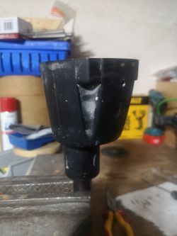 Czarna część mechaniczna zamocowana w imadle na stole warsztatowym.