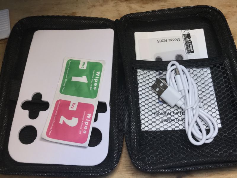 R36S console accessories in a case: USB cable, wipes, manual, and screen protector