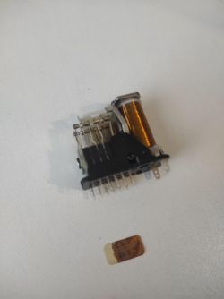 Przekaźnik z widocznymi zestyki i cewką miedzianą na białym tle.