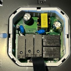 Open Thermostat with Circuit Board View of an open thermostat with visible electronic components on a circuit board.