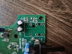 Zbliżenie płytki PCB z otworami po gnieździe jack 6,3 mm i opisami R80, C146 oraz „HEADPHONE”.