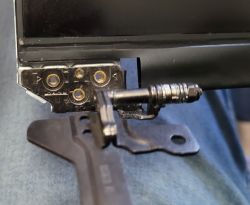 Zbliżenie na zawias laptopa z metalowym wspornikiem i śrubą na niebieskim materiale