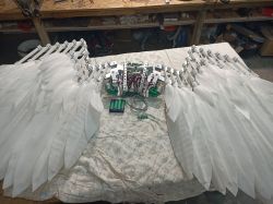 Mechaniczne skrzydła z napędem, wykonane z białego materiału i aluminium, leżące na stole.