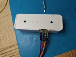 Plastic enclosure with holes and attached wires on a blue background.