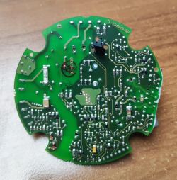 Okrągła zielona płytka drukowana z widocznymi ścieżkami i elementami elektronicznymi.