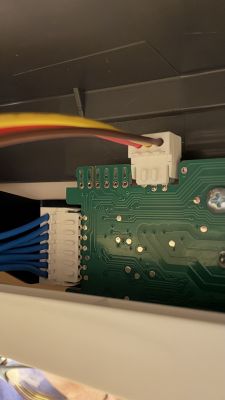 Close-up of a PCB with white connectors and colored wires inside a device housing