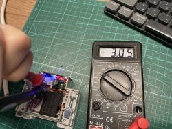 Voltage Measurement with Multimeter Digital multimeter showing -3.05 V next to an electronic module with test probes.
