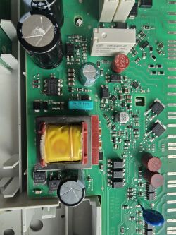 Zbliżenie na płytkę drukowaną z różnymi komponentami elektronicznymi, w tym rezystorami i kondensatorami.