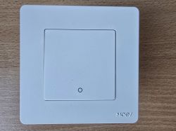 White, square light switch on a wooden surface.