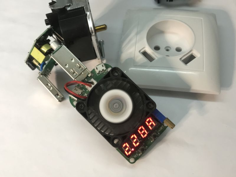 Disassembled wall socket with USB ports and an electronic load module with fan and LED display