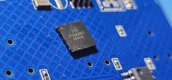 Close-up of a blue circuit board with an SMD chip mounted on it.