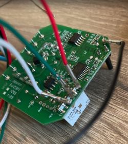 Close-up of a green PCB with colored wires and surface-mounted integrated circuits.