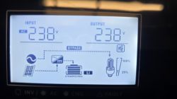 Wyświetlacz inwertera pokazujący napięcie wejściowe i wyjściowe 238 V oraz tryb bypass