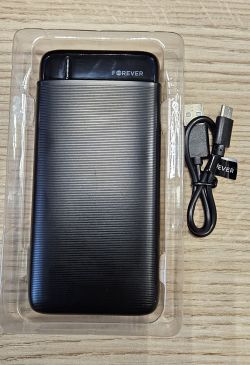 Czarny power bank Forever TB-100L 20000 mAh w opakowaniu z kablem micro-USB obok.
