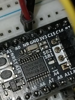 Zbliżenie mikroprocesora na płytce prototypowej z oznaczeniami pinów.