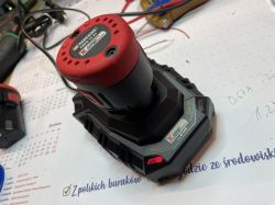 Ładowarka Parkside X12V Team z podłączonym akumulatorem na biurku.