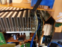 Wnętrze elektronicznego urządzenia z płytką drukowaną, radiatorami i okablowaniem.