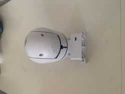 White surveillance camera on a rectangular mount, placed on a light surface.