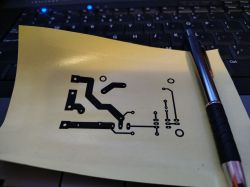Wydruk projektu PCB na żółtym papierze, leżący na klawiaturze z długopisem obok