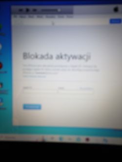 Rozmyty ekran komputera z komunikatem o blokadzie aktywacji iPhone'a.