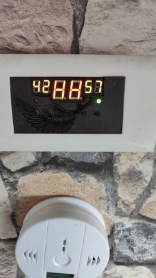 Wyświetlacz o oznaczeniu HH i okrągłe urządzenie na tle kamiennej ściany.