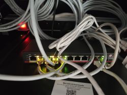 Przełącznik sieciowy PoE z podłączonymi przewodami Ethernet i świecącymi diodami portów