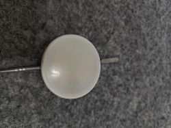 Energy+ Smart GU10 LED Bulb on Surface View of a white LED bulb lying on a gray surface with a teardown tool.