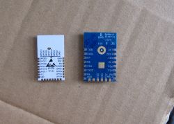 OPL1000 module on a cardboard background, showing pins and markings.