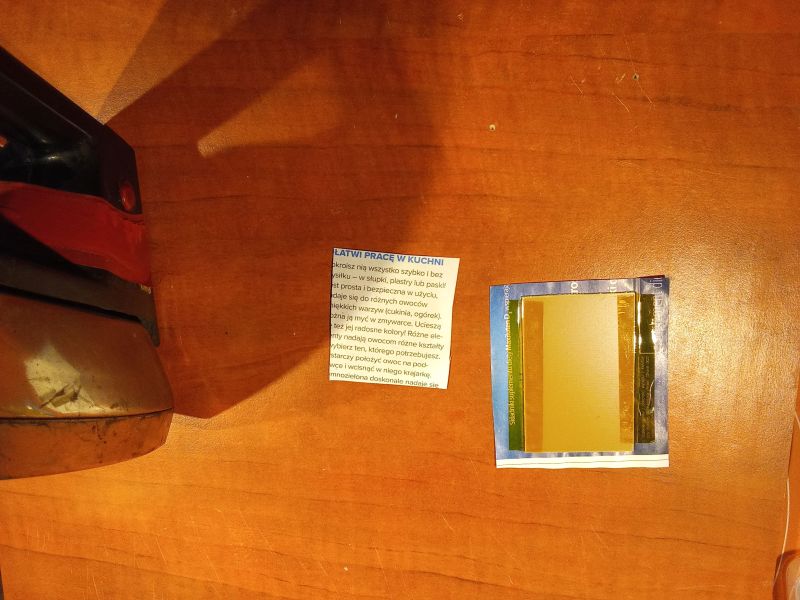 A paper with text on a wooden table and a metal object.