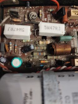 Zbliżenie na płytkę drukowaną z różnymi komponentami elektronicznymi, w tym rezystorami, kondensatorami i cewką.