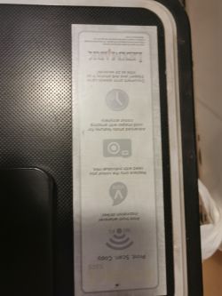 Fragment drukarki Lexmark z widoczną naklejką informacyjną na obudowie, zdjęcie zrobione z góry.