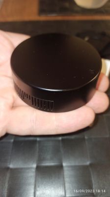 Black, round AuBees IR Blaster held in hand.