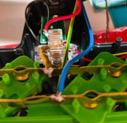 Inside a power strip: green socket modules and red, blue, and yellow‑green wires in a black casing