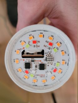 Round LED circuit board with multicolor LEDs and electronic components, held in a hand