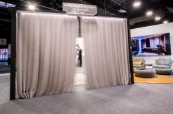 Gray automated sliding curtains at a trade booth, with the sign “automatyka przesłon okiennych” above.