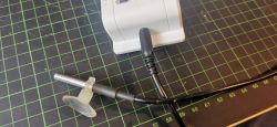 External sensor connected via a 3.5 mm plug to a white device on a measurement grid.